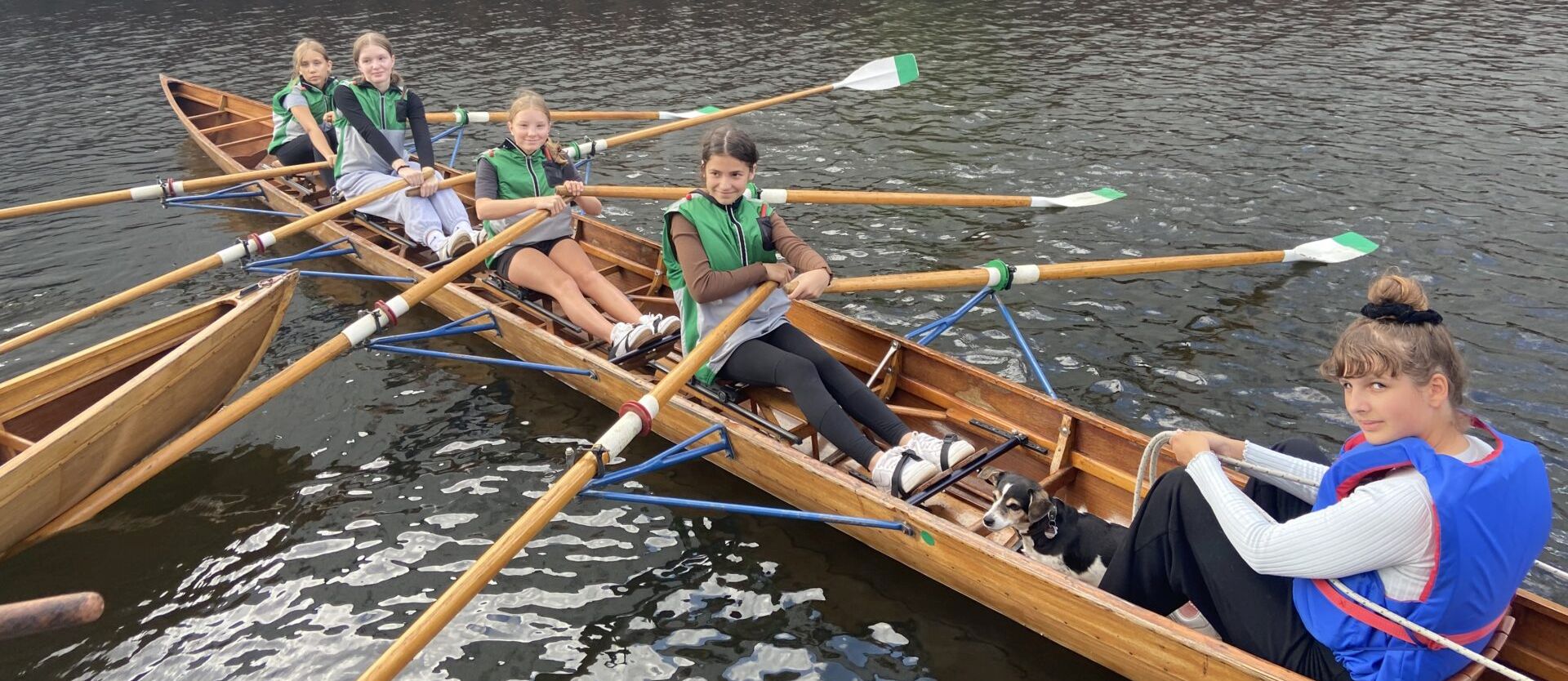Fünf Schülerinnen im Ruderboot auf der Elbe beim Anlegen im Hafen